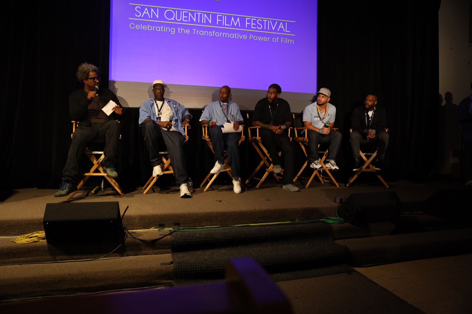 Filmmakers seated on stage beneath the San Quentin Film Festival screen