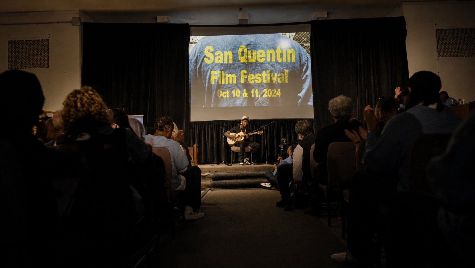 The audience watches a performance beneath the San Quentin Film Festival screen